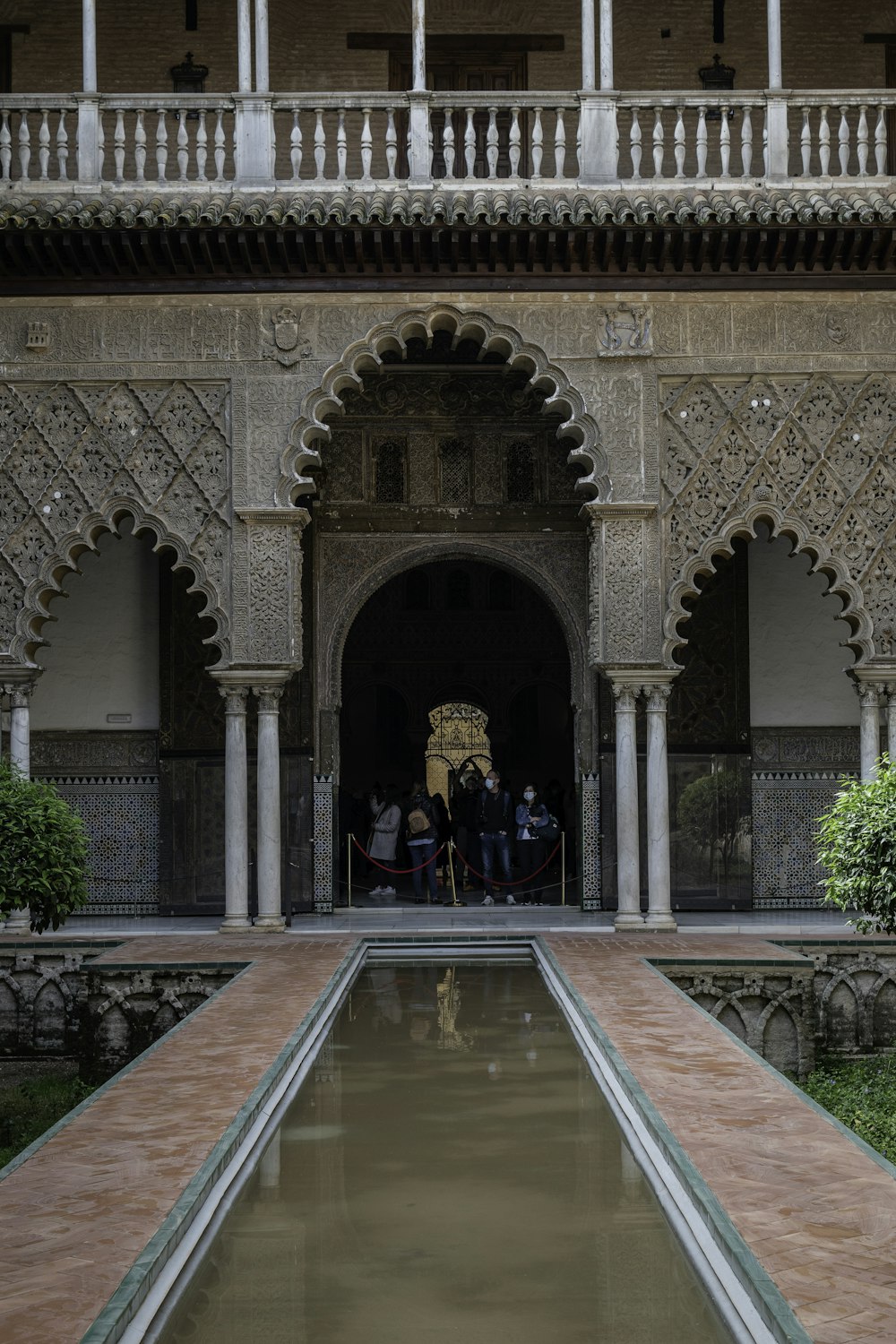 a group of people standing on a balcony above a pool of water