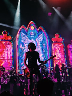a person playing a guitar on a stage with a crowd watching