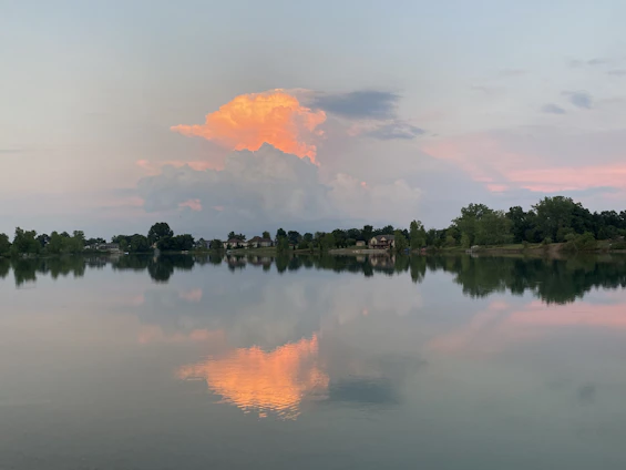 A warm photo of Scott Buitta standing by a serene lake with charming homes in the background.