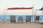 a group of chairs under a red umbrella on a beach