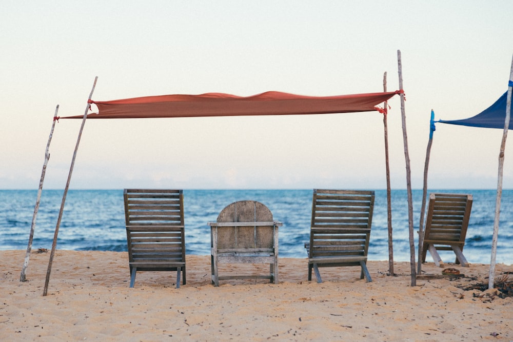 Eine Gruppe von Stühlen unter einem roten Sonnenschirm am Strand