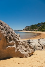 a body of water with a rocky shore and trees on the side