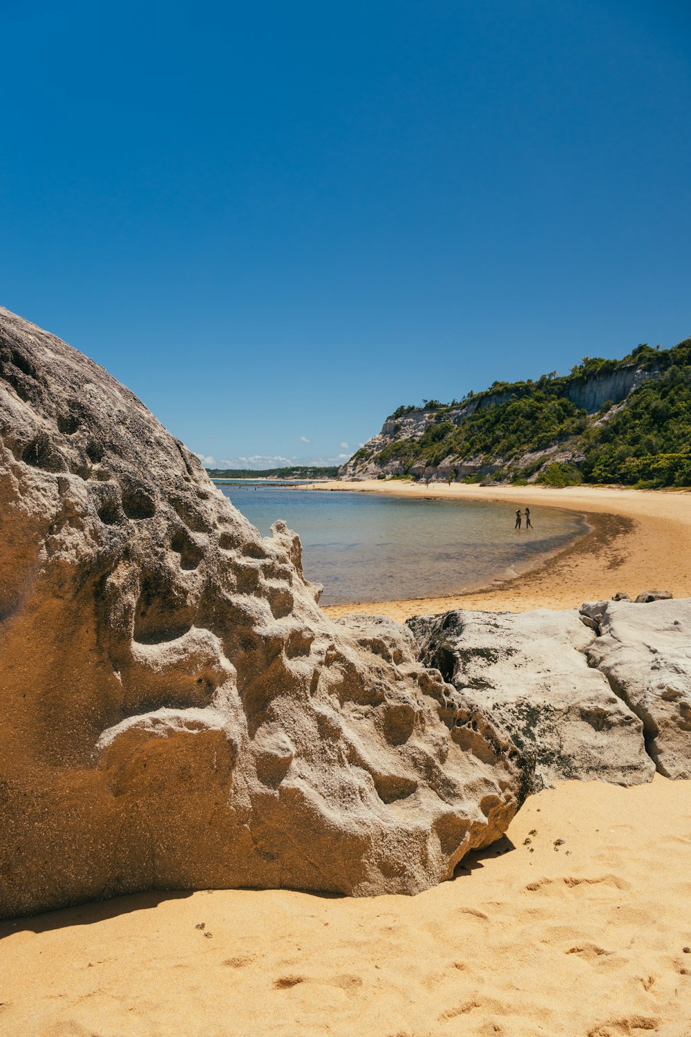 a body of water with a rocky shore and trees on the side