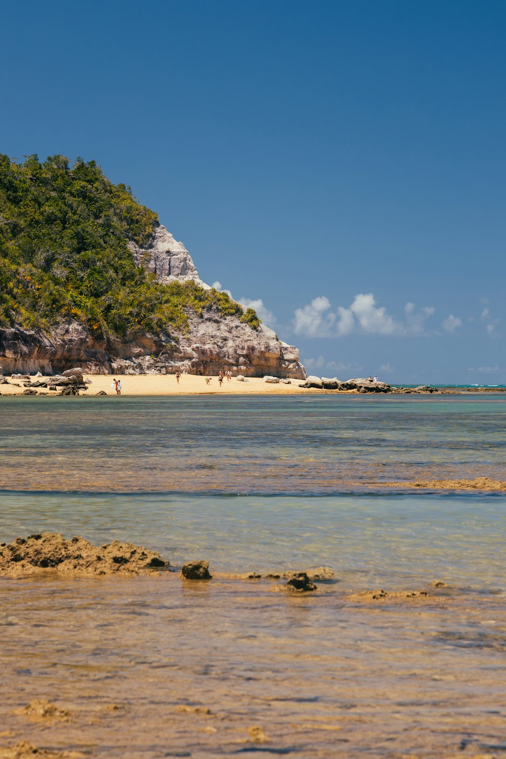 a beach with a large rock cliff