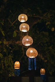 Warm glowing lanterns hanging from tree branches, creating a welcoming evening ambiance.