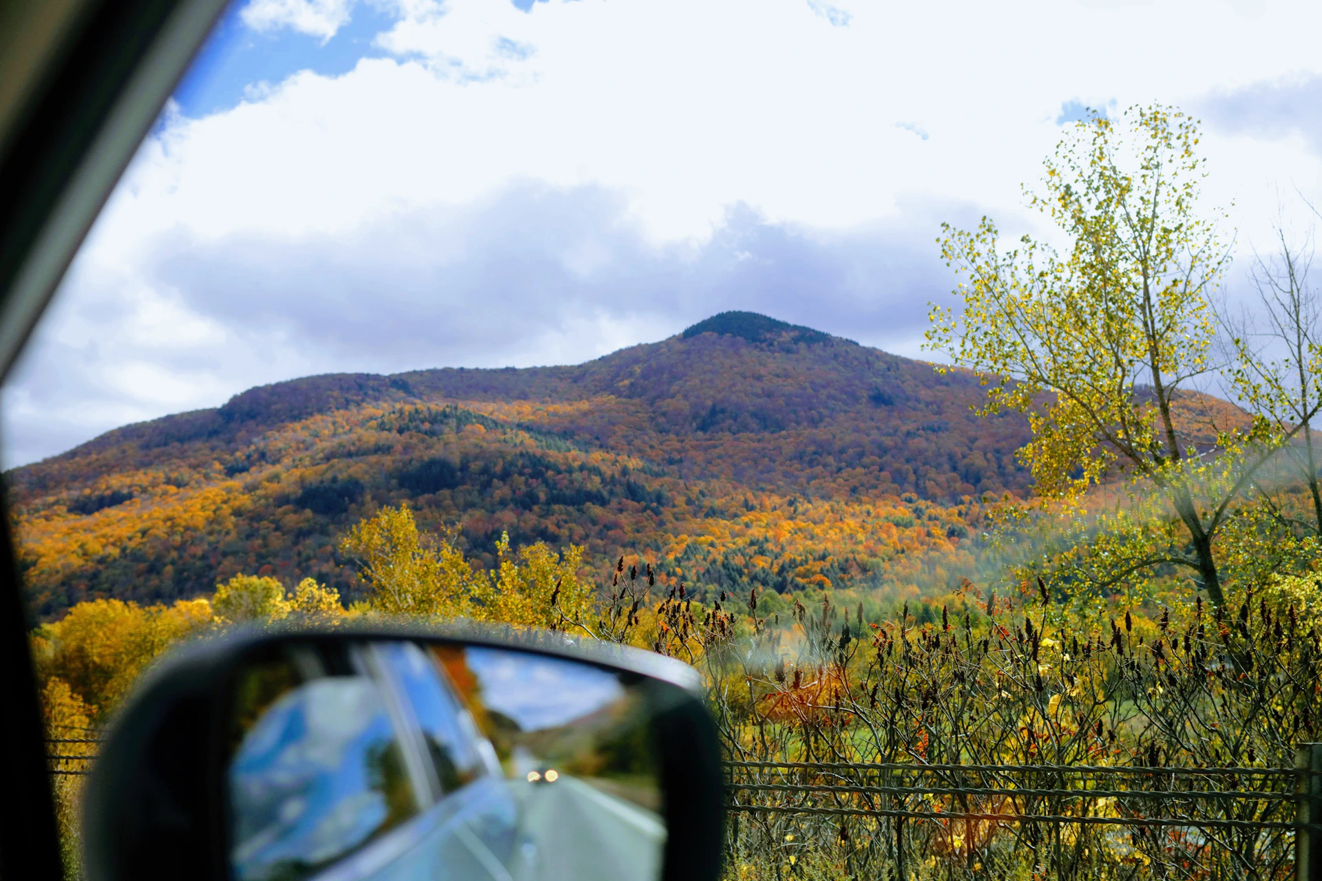 a car driving on a road with trees and mountains in the background