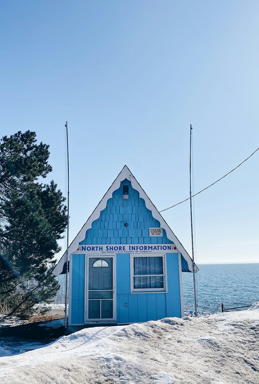 a small blue building with a white roof and a blue door surrounded by snow