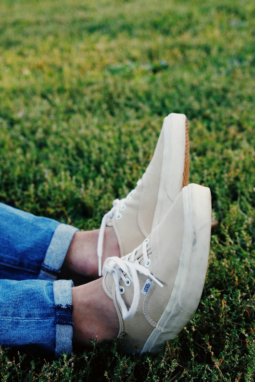 a person's feet in white shoes on grass