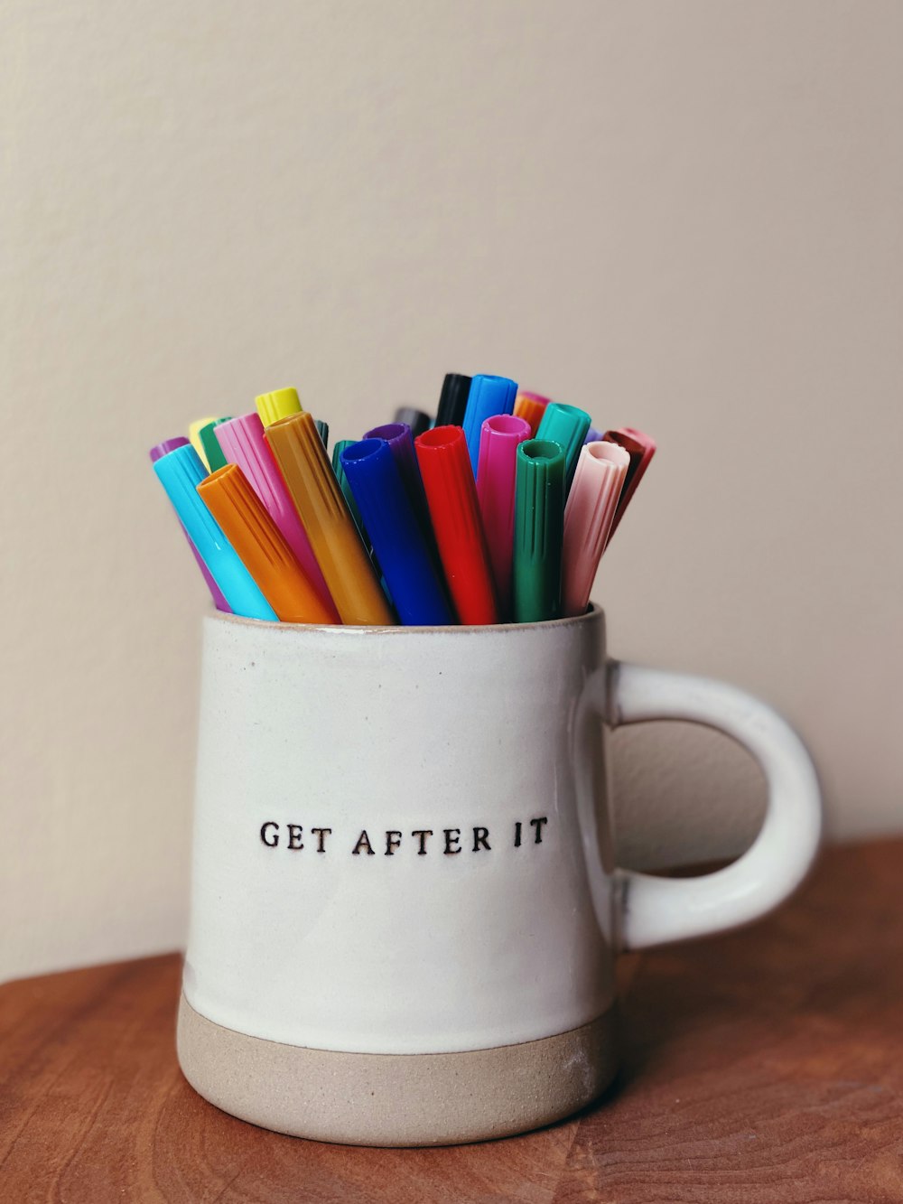 a white mug with a group of colored pencils in it