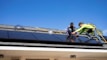 A technician installing solar panels on a rooftop on a sunny day