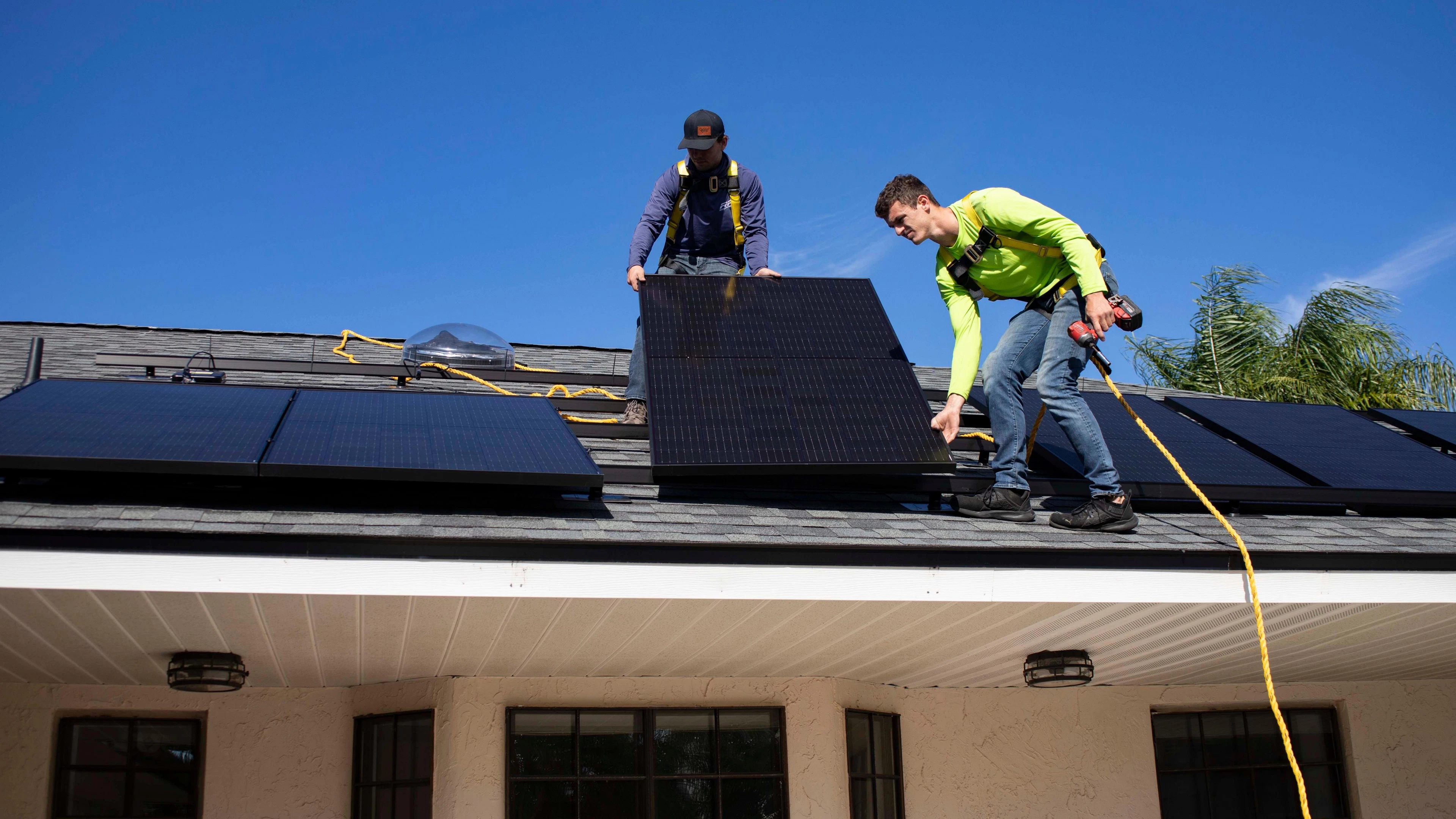Installateurs qui posent un panneau photovoltaïque sur un toit