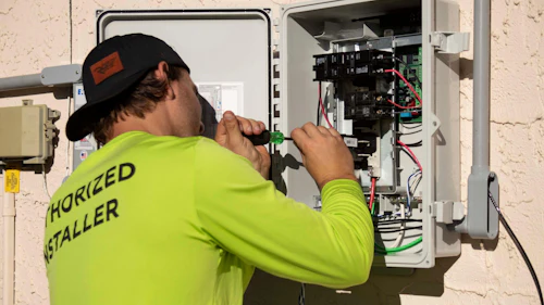 Electrician using a screwdriver on an electrical panel