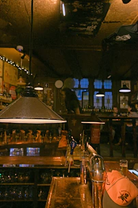 Interior of Ježkove oči brewery bar with wooden tables, industrial lamps, and friends enjoying craft beer