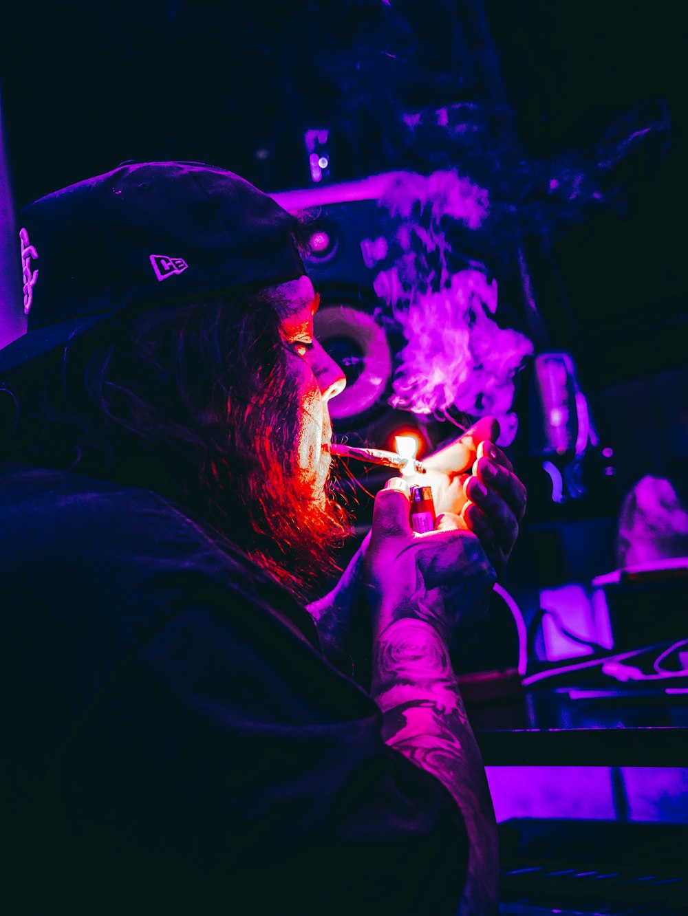 a man with a beard and a hat holding a cigarette in front of a crowd of people