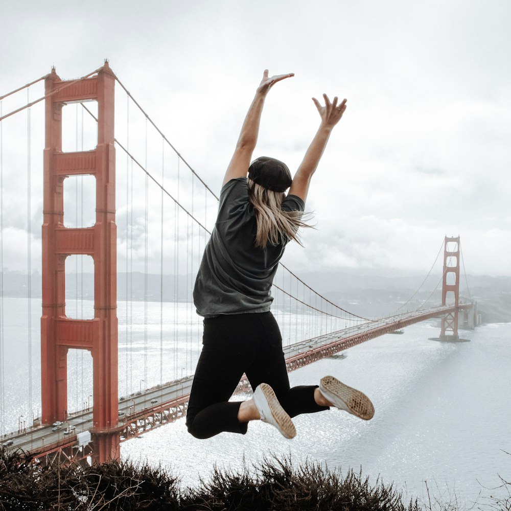 a person jumping in the air with a bridge in the background
