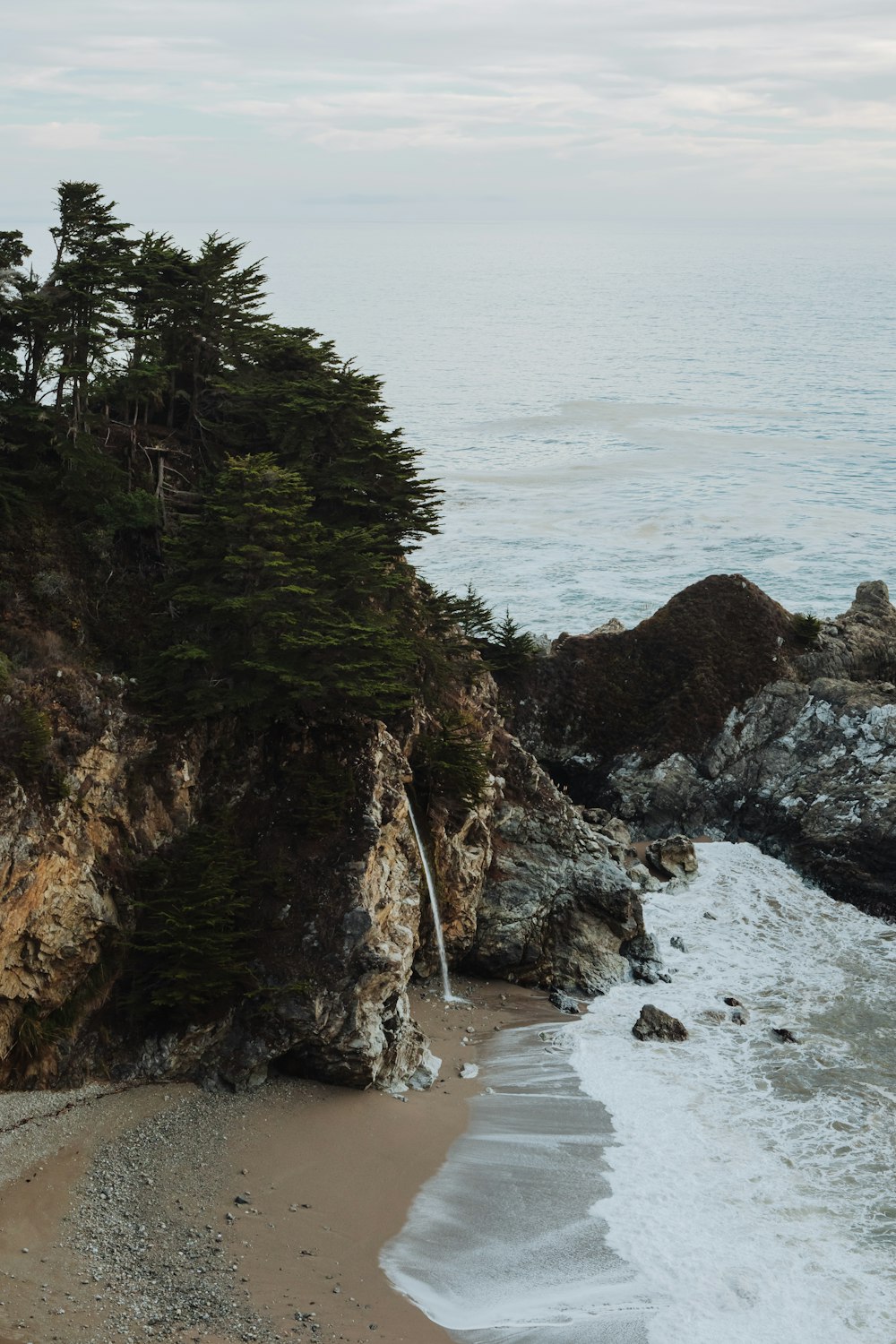 a rocky cliff with trees and water below