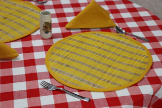 a plate with a yellow circle on it and a fork on it place mats Kanha Universal Export