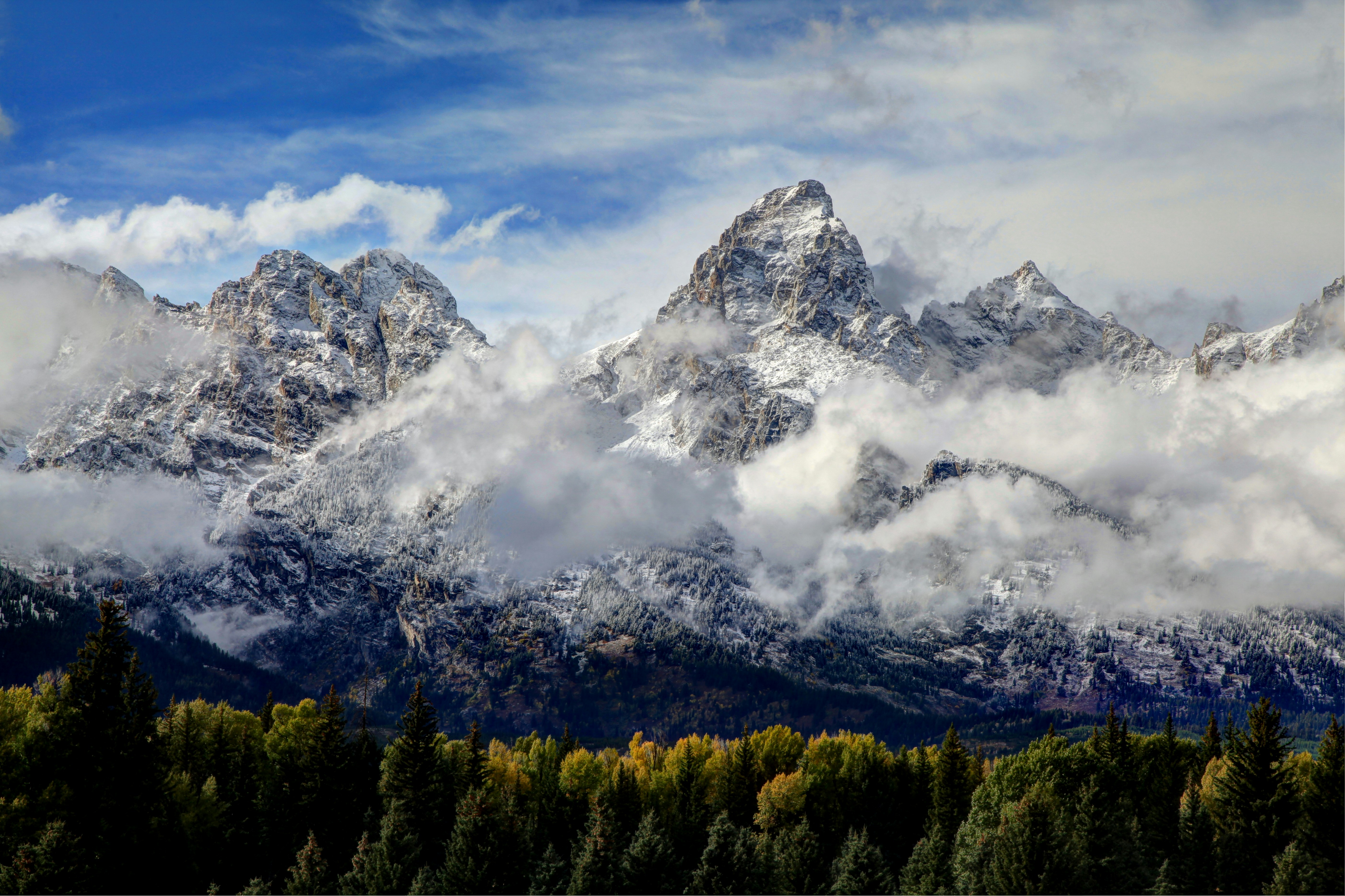 a mountain with clouds and trees below