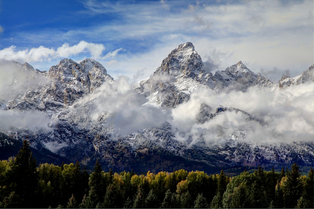 a mountain with clouds and trees below