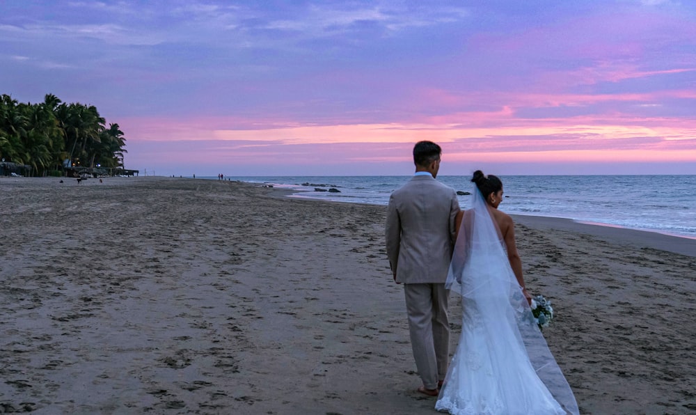 a man and woman holding hands on a beach