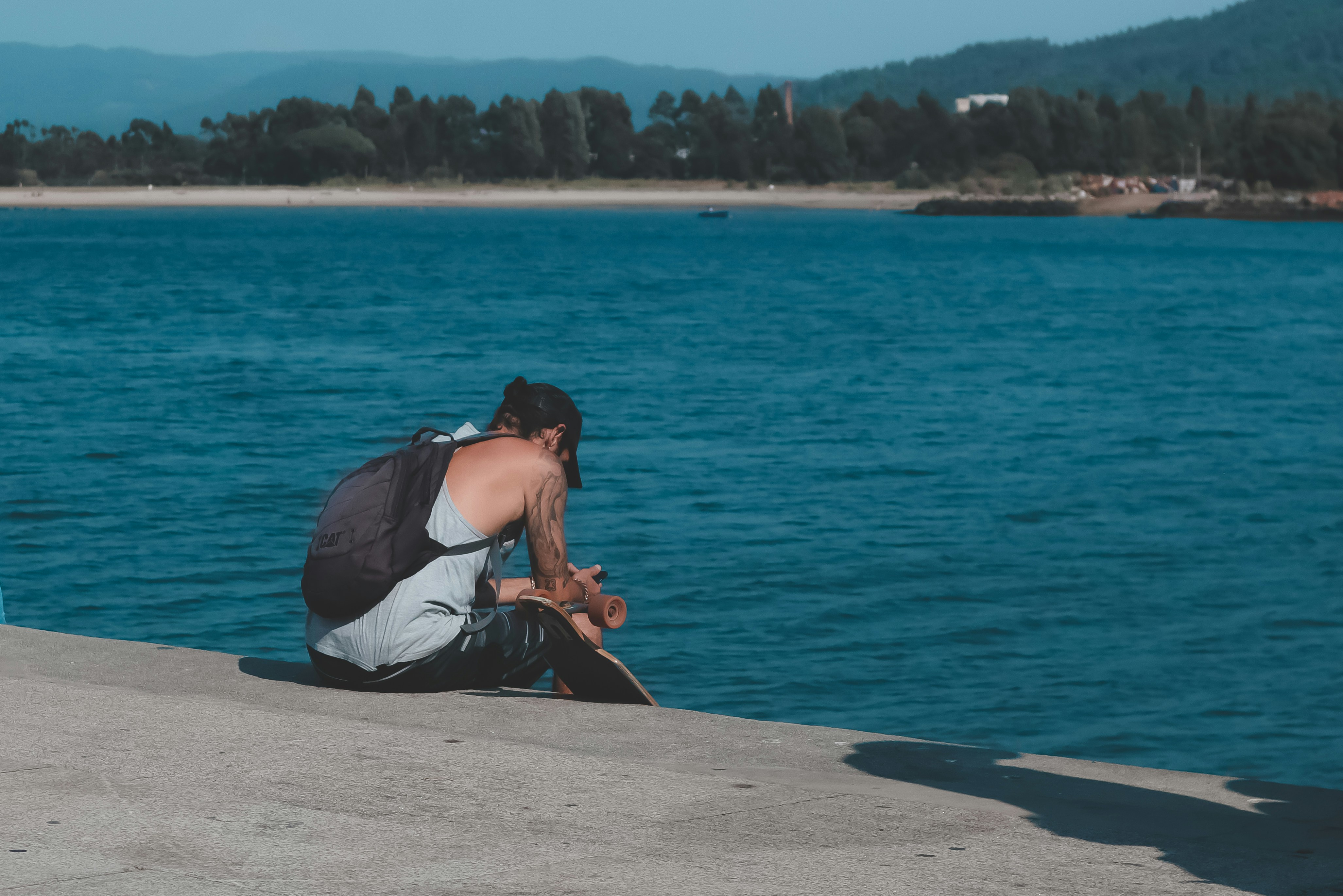a man sitting on a ledge looking at a body of water