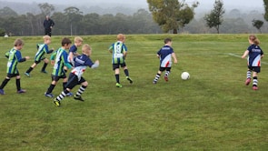 Children participating in an energetic outdoor sports activity on a grassy field.