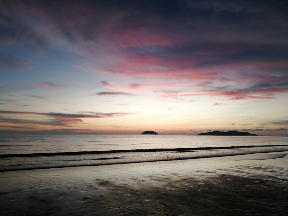 a beach with a body of water and a sunset