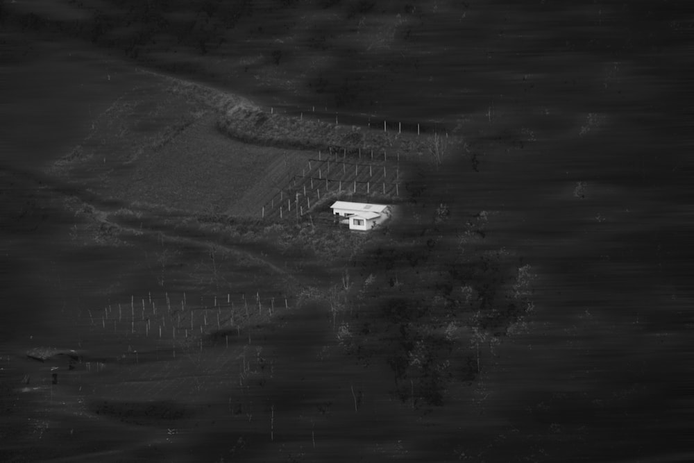 a black and white photo of a building on a hill with a fence