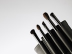 Set of sleek makeup brushes neatly arranged on a marble countertop with soft natural lighting