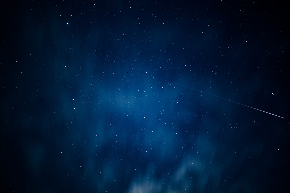a starry night sky with a jet trail