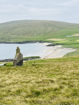 a stone tower on a grassy hill overlooking a body of water
