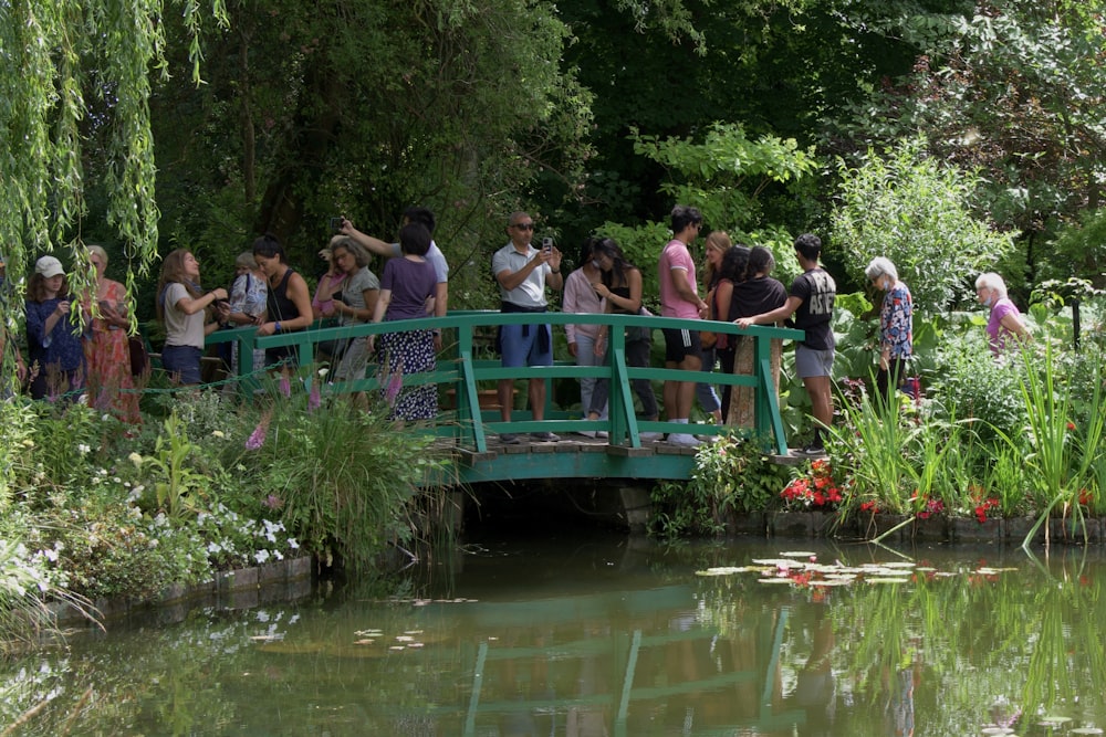 a group of people standing on a bridge over a pond