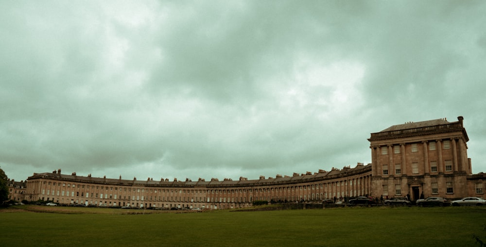 a large building with a grass field in front of it with Royal Crescent in the background