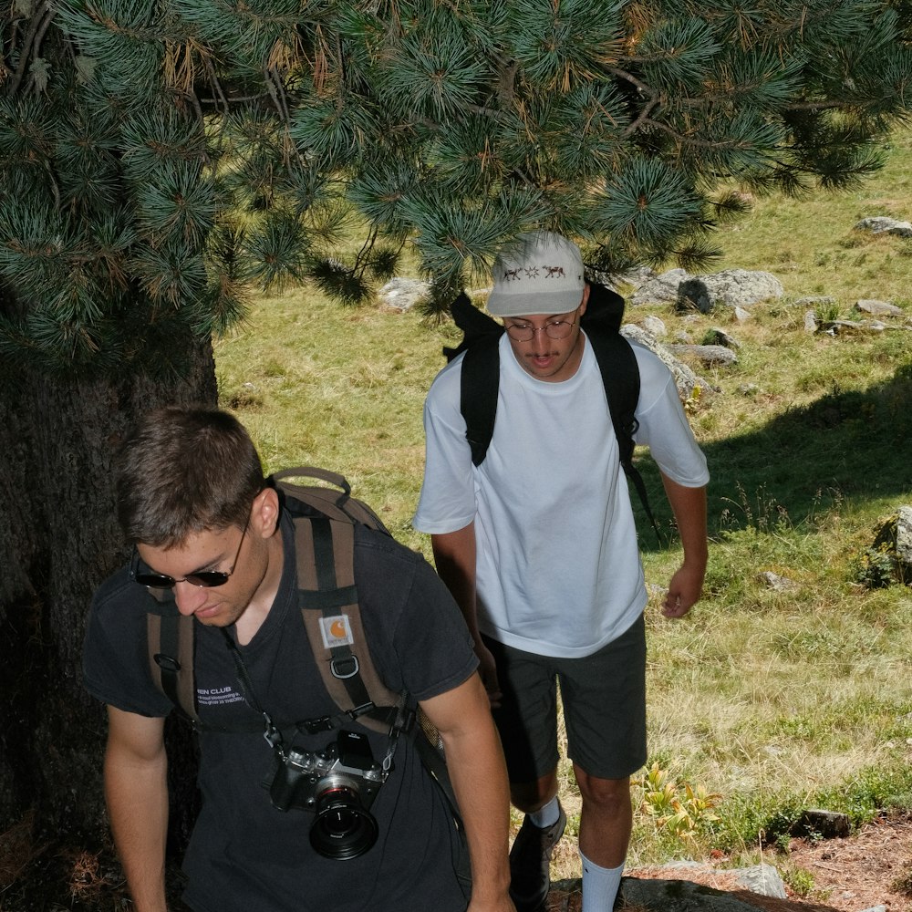 a couple of men with backpacks looking at a camera