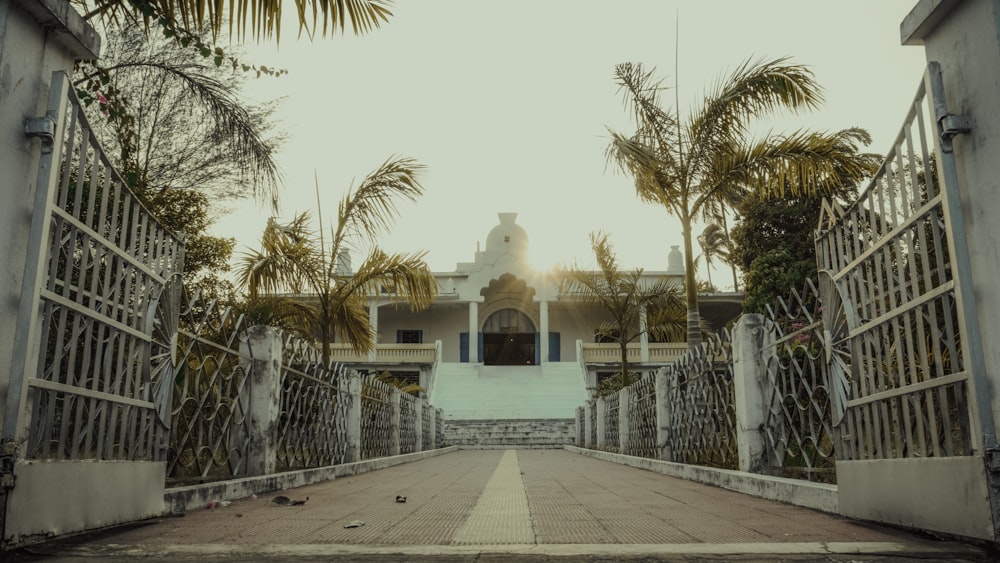a gated walkway leading to a building with palm trees
