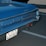 A vintage blue Pontiac GTO, featuring a Swiss license plate, is parked in a lot. The rear section of the car is visible, showing the brand logo and tail lights.
