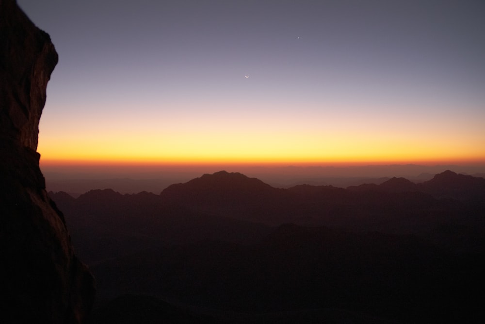 a sunset over a body of water with a mountain in the background