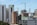 High-rise buildings and construction cranes dominate the urban landscape. A combination of modern skyscrapers and mid-rise buildings, with a construction site featuring cranes. Some buildings have signage, indicating institutional use.