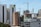 High-rise buildings and construction cranes dominate the urban landscape. A combination of modern skyscrapers and mid-rise buildings, with a construction site featuring cranes. Some buildings have signage, indicating institutional use.