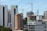 High-rise buildings and construction cranes dominate the urban landscape. A combination of modern skyscrapers and mid-rise buildings, with a construction site featuring cranes. Some buildings have signage, indicating institutional use.