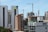 High-rise buildings and construction cranes dominate the urban landscape. A combination of modern skyscrapers and mid-rise buildings, with a construction site featuring cranes. Some buildings have signage, indicating institutional use.