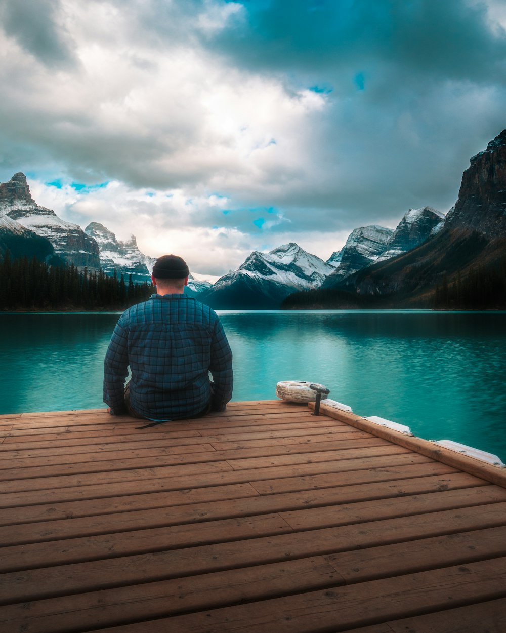 a person sitting on a dock looking at a body of water