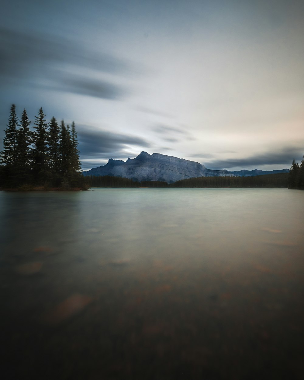 a lake with trees and mountains in the background