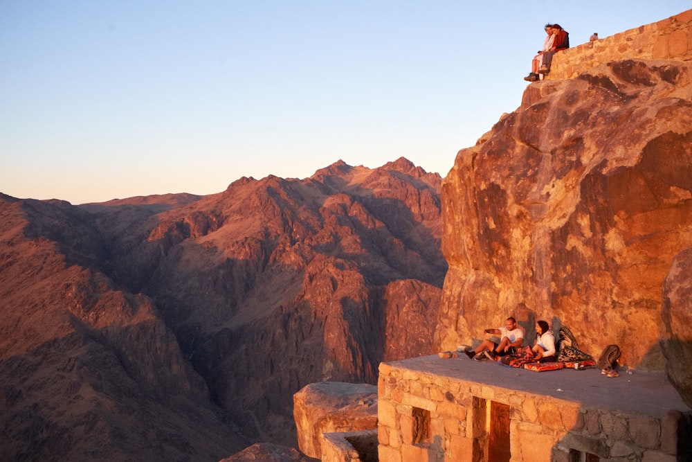 a group of people sitting on a rock ledge