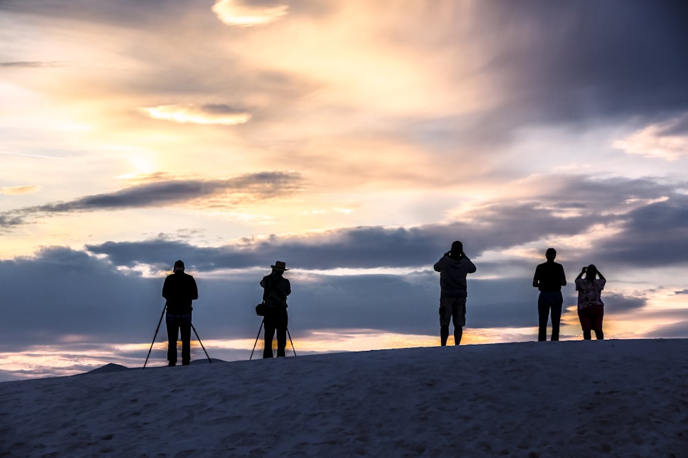 a group of people standing on a snowy hill with a cloudy sky