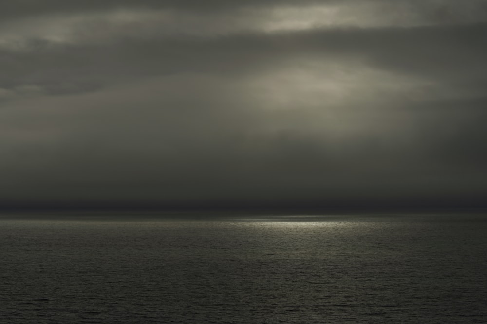 a body of water with a cloudy sky above it