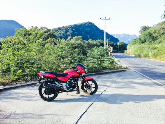 Side view of a red motorcycle parked near a mountain road in Salta.