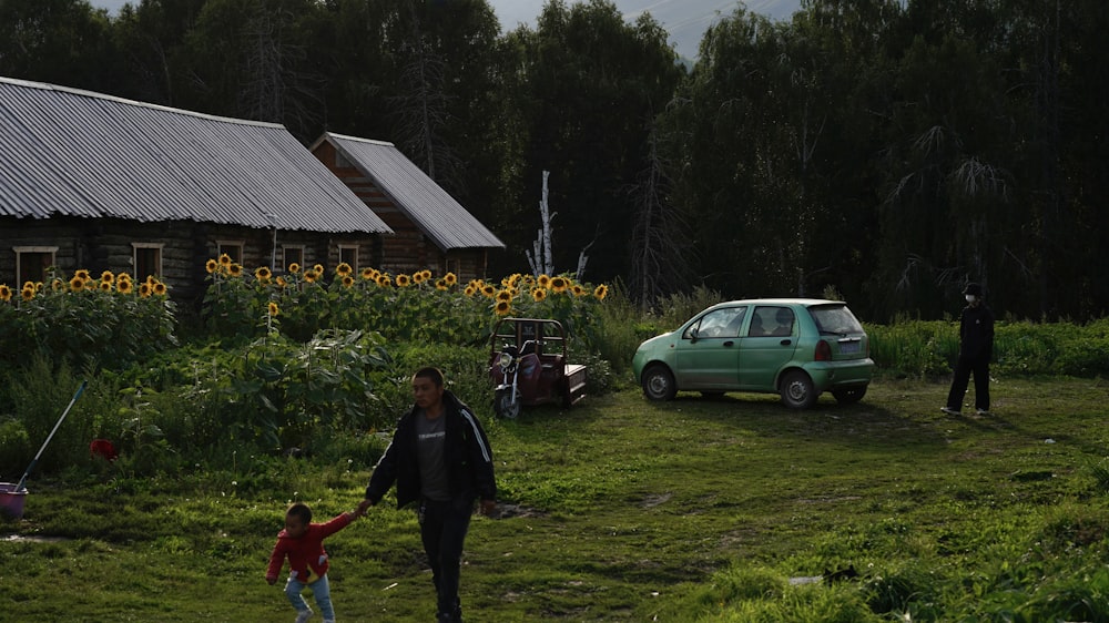 uma pessoa e uma criança brincando em um quintal com um carro e uma casa