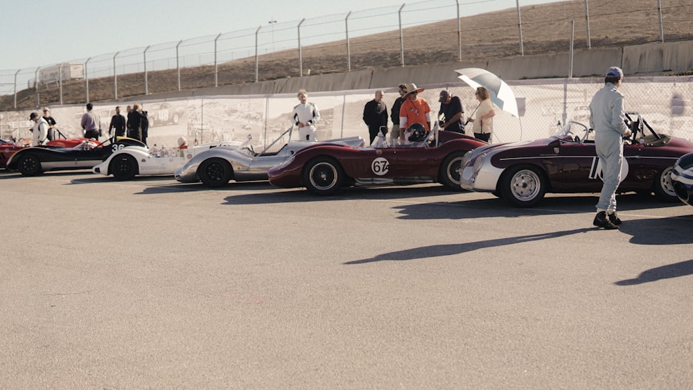 a group of people standing around a row of cars