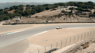 Wide shot of a vintage racing car on a historic circuit with lush green surroundings.